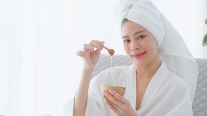 Young woman in bathrobe enjoying honey skin spa.