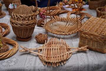 wicker products made of natural vines in the form of baskets, eggs, boxes, coasters, wreaths, on the table close-up. The concept of making interior items from natural materials