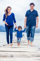 Young couple waiting for their second baby having fun with their baby girl at the beautiful white beach of Lake Tota located in the department of Boyaca at 3,015 meters above sea level in Colombia