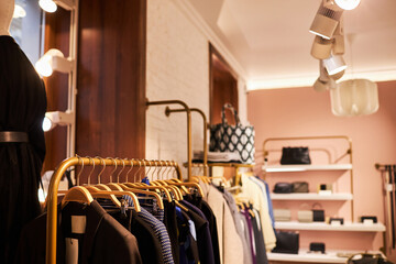 Naklejka na ściany i meble Background image of clothing boutique interior with clothes on golden racks, copy space
