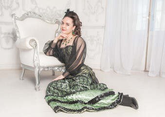 Beautiful young smiling woman wearing green medieval vintage Victorian Style dress sitting on the...