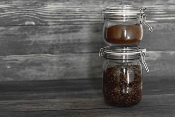 ground coffee and beans in glass jars on a dark background