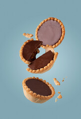 shortcrust pastry cakes with chocolate, with crumbs, on a blue background, flying food