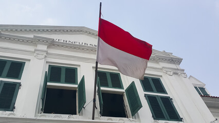 The Indonesian red and white flag flutters on top of the old Dutch heritage building