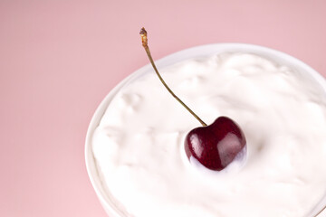 cherry in a cup with cottage cheese, on a pink background, copy space