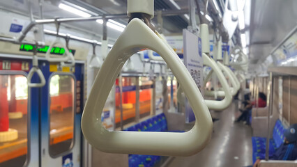 View of handles on ceiling rails for standing passenger. Handle on the commuter line train, prevent...