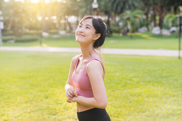 Naklejka na ściany i meble Capture the happiness of a young, beautiful Asian woman in her 30s, smiling and looking at the camera in a park at sunset. Embrace the wellness living concept.