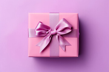 Pink gift box with pink ribbon and bow on purple background.