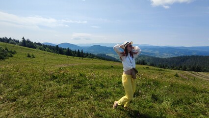 Naklejka premium Traveling in summer Ukraine. Trip to Carpathian mountains. Woman tourist relaxing in flowers admiring view