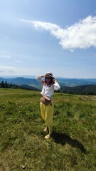 Fototapeta premium Traveling in summer Ukraine. Trip to Carpathian mountains. Woman tourist relaxing in flowers admiring view