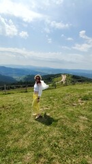 Traveling in summer Ukraine. Trip to Carpathian mountains. Woman tourist relaxing in flowers admiring view