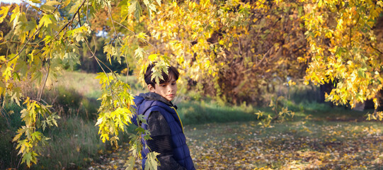 Banner cute teenager in blu jacket on the background of autumn leaves.Autumn background. Copy space