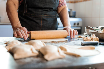 Unrecognizable Latin Woman Kneading Dough with a Rolling Pin, for making Empanadas in her Countryside Home Kitchen