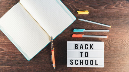 Back to school concept. School supplies on wooden background. Back to school lettering on white letter board. Copy space for text. Selective focus included