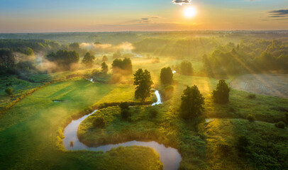 Beautiful summer sunrise over the river covered with morning fog