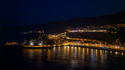 Italy, July 2023: night aerial view from the drone of the medieval village of Scilla in Calabria, with its castle, tourist port and beaches with restaurants