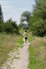 A boy walks along a path in a city park