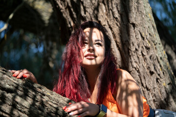 Portrait of a girl on a tree in a city park in summer