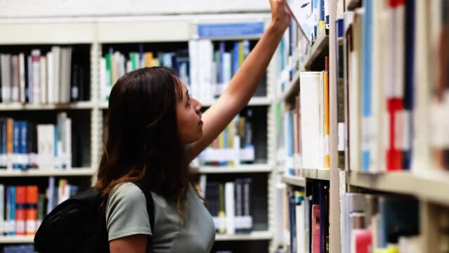 young student woman looking for a book in a library at a university in colombia
