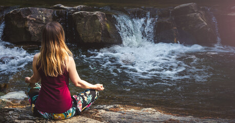 Woman doing yoga on the stone at the mountain river. Carpathians