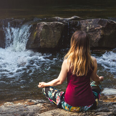 Woman doing yoga on the stone at the mountain river. Carpathians
