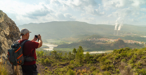 A hiker takes a photo of the mountainous landscape.