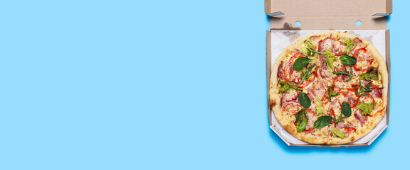 fresh hot pizza in an open package on a blue background. Top view, flat lay. Banner