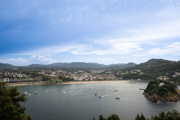 boats in the sea in the bahia de la concha Donosita-San Sebastian Spain on sunny summer day. Rocky island Isla de Santa Clara rises from the water of the Bay of  Biscay