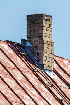 An old brick house chimney above a tin roof