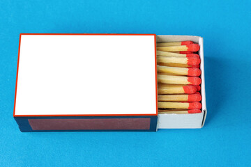 A horizontal box of matches with red match heads on a blue background