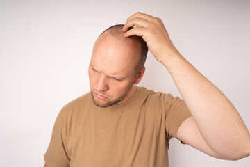 Obraz premium Young man in a brown t-shirt scratching his head and thinking about a better solution