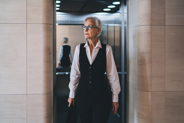 Senior serious woman coming out of elevator