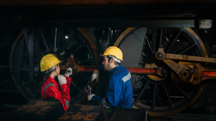 Obraz premium Industrial engineers inspect and perform maintenance on the machines at factory machines. Efficient Machinery Operation and Teamwork in the Manufacturing Industry