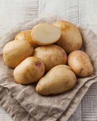 Washed potatoes whole and half on a napkin on a wooden table. Vegetables, root crops. Harvesting.