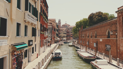 Canal in Venice, Boats and gondolas with tourists float along canal, on sunny day