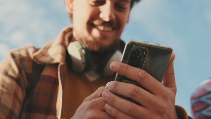 Close-up of a young man using a mobile phone. Portrait of a happy guy typing a social media message on his mobile phone