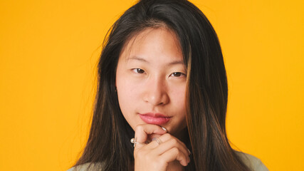 Naklejka premium Close-up, girl in gray top looking at camera, smiling and flirting isolated on yellow background in studio