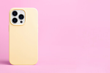 iPhone 15 Pro in yellow phone case back view isolated on pink background, phone case mockup banner with place for text on the right