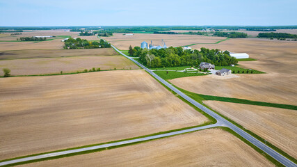 Aerial professionally mowed green lawn house property near farmland with empty, plowed fields