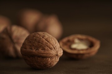 Close-up of walnut kernels and shelled nuts on a wooden table on a dark background.Healthy food, quick snack.