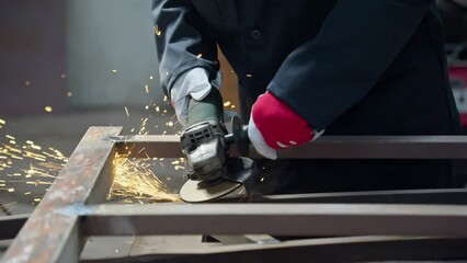 Factory worker grinding metal. Worker in protective clothing. Close-up of bright sparks and flashes in 4K, UHD - Powered by Adobe