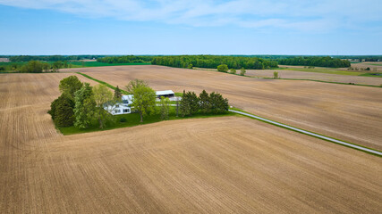 Fototapeta na wymiar Clean farmhouse landscape property aerial with green runoff ditches, paved road, empty fields aerial