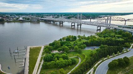 White truss, suspension bridges with rusty arch bridge on Ohio River near docks and greenery aerial