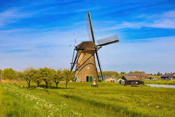 Fototapeta na wymiar A large windmill stands on the edge of the canal to drain the water from the pastures, to obtain fertile land. Netherlands