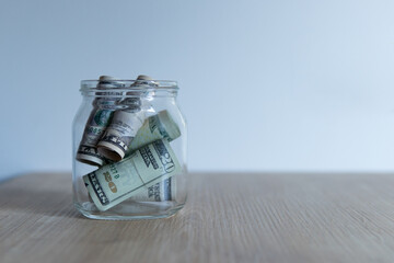 money storage. open transparent jar with dollars inside on a wooden table.