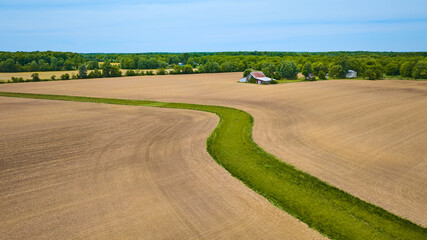 Flat farmland terrain with snaking river of green grass aerial