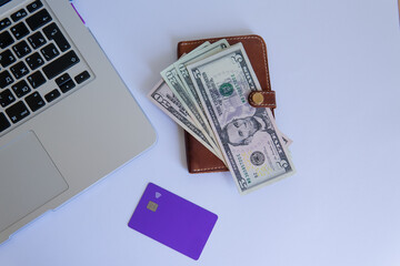 business composition with money. dollars on a wallet with a credit card with a laptop on a white background top view