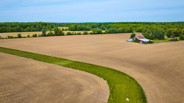 Aerial Flat Farmland With Barren Fields And Patch Of Green Grass Snaking Through Desert Area