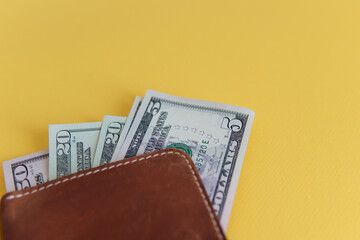 dollars in a leather wallet close-up on a yellow background. monetary composition of banknotes.