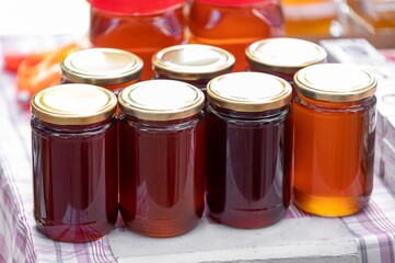 jars of honey of different varieties on farm market